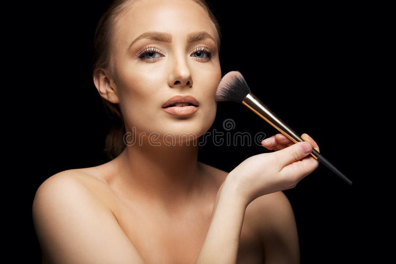 Beautiful young woman applying foundation royalty free stock photography